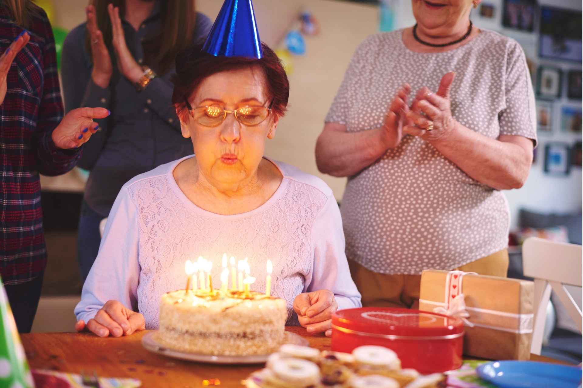 senior blows out candles on birthday cake