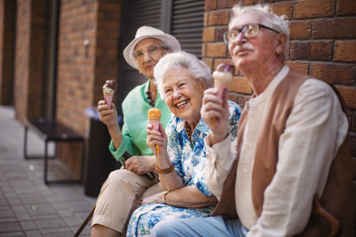 Portrait of three senior friends eating ice cream together on a bench.