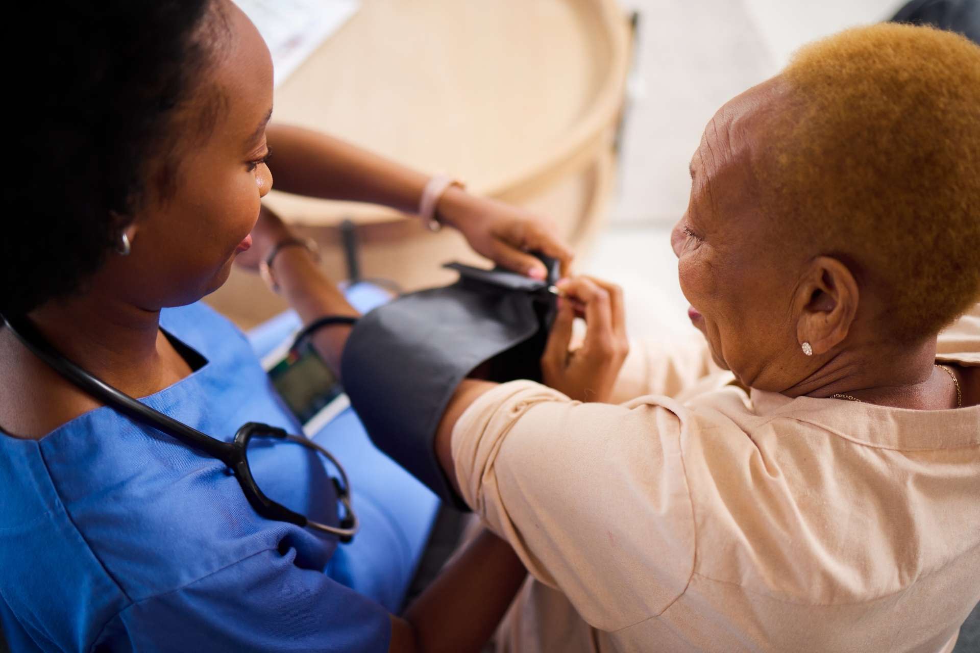 A senior woman getting her blood pressure checked by a nurse.